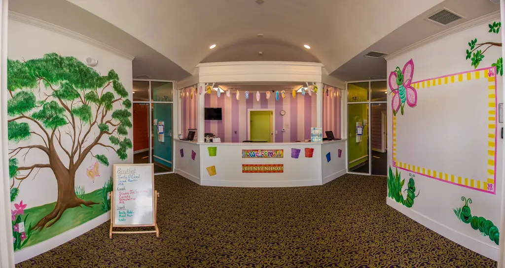 Growing Room lobby with a painted tree mural and a Welcome, Bienvenidos banner